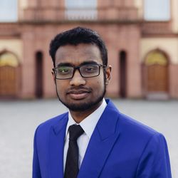 Portrait von Md. Najmul Ali, einem Masterstudenten der VWL. Er hat kurze schwarze Haare, trägt eine Brille und ein weißes Hemd mit schwarzer Krawatte unter einem blauen Jackett.