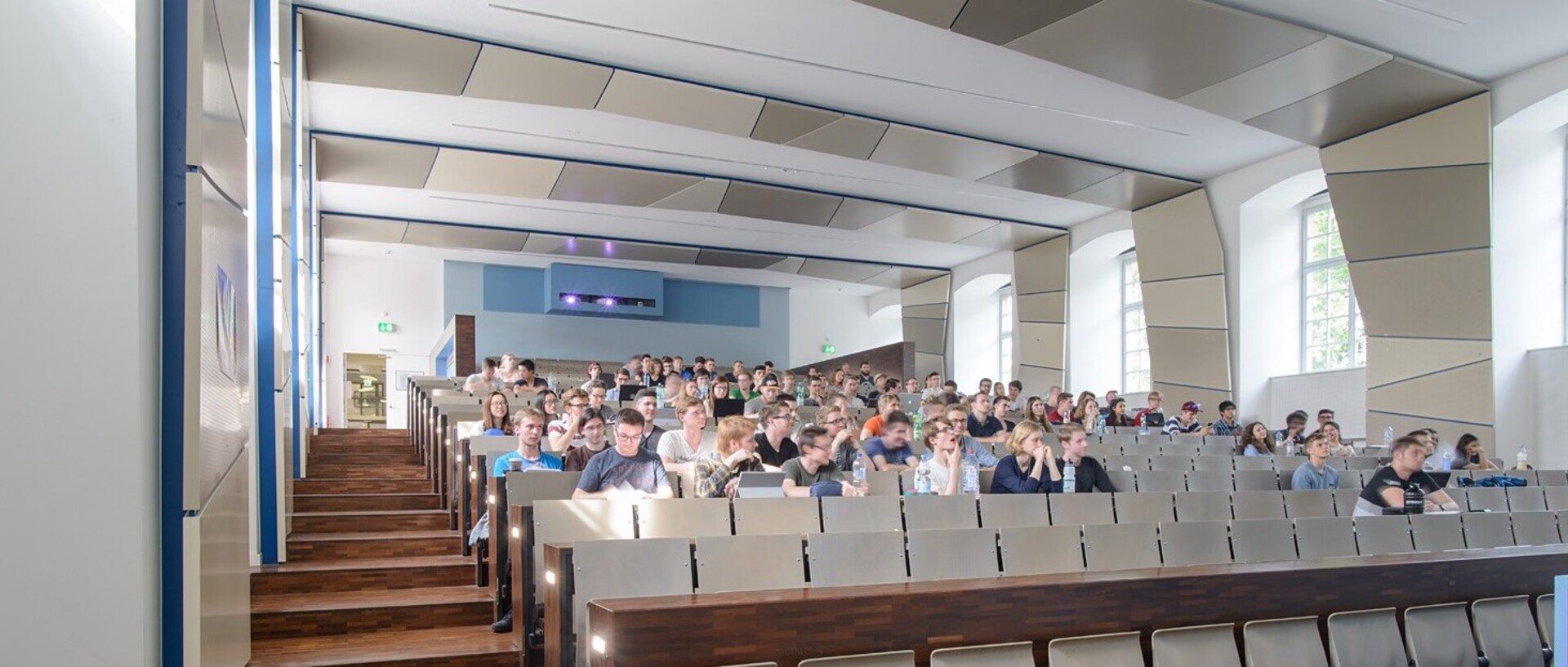 Blick von vorne in den Hörsaal SO108 im Ostflügel der Universität. In dem Hörsaal sitzen viele Studierende.