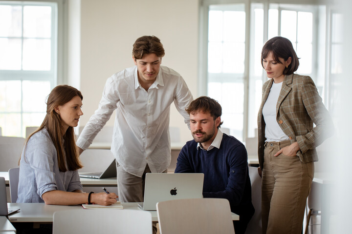 Eine Gruppe von vier Personen diskutiert über die Inhalt eines LapTop-Screens