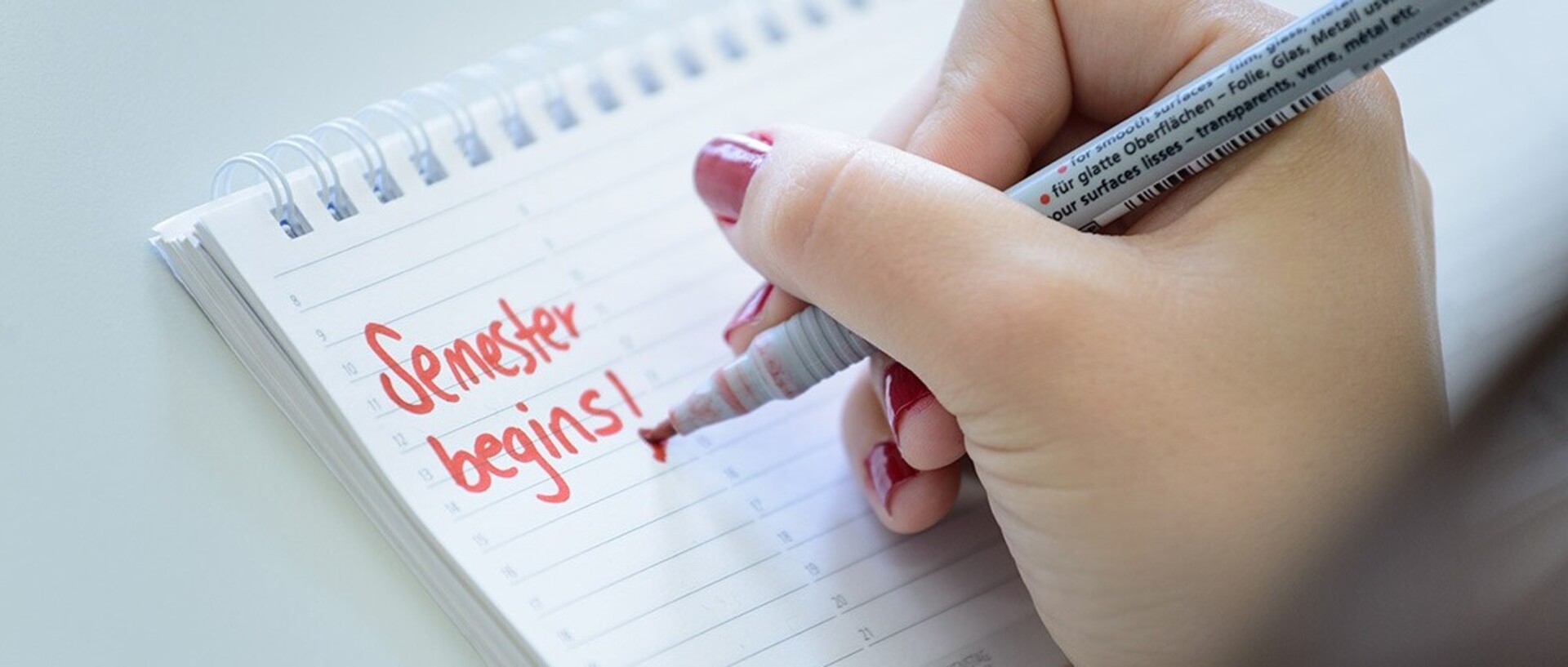 Mit rotem Stift wird in einen Kalender „Semester begins!“ eingetragen.