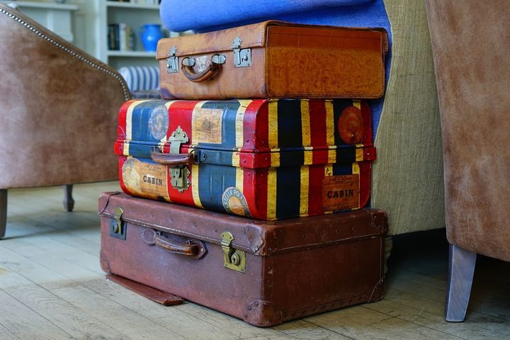Three stacked old suitcases in front of a seating area.