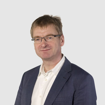 Prof. Theissen hat kurze Haare und eine Brille. Er trägt ein blaues Jacket und ein weißes Hemd.